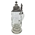 A glass mug with an ornate pewter lid and a figure of Germania