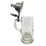 A glass mug with an ornate pewter lid and a figure of Germania