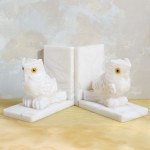 A set of two bookends decorated with an owl motif, made of white marble.