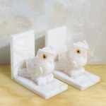 A set of two bookends decorated with an owl motif, made of white marble.