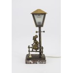 A lamp with a figurine of a girl sitting on a bench