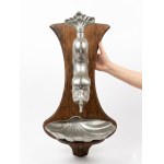 Decorative wall-mounted sink made of pewter and wood, featuring a dolphin and seashell motif