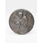 Circular plaque depicting St. Francis of Assisi; embossed metal with a silver finish; 10 cm