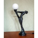 A large ceramic lamp in the Art Deco style—a woman holding a lantern.