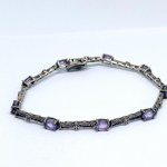 A thin silver bracelet with natural amethysts