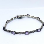 A thin silver bracelet with natural amethysts