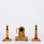 A yellow marble triptych consisting of two candlesticks and a small table clock