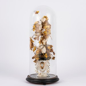 Vase en porcelaine blanche et dorée contenant un arrangement floral artificiel, à l'intérieur d'une cloche en verre