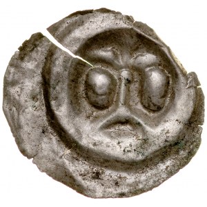 Brakteat guziczkowy II poł. XIII w., nieokreślona dzielnica, Av.: Lilia na długim słupie oparta o łuk, pod bokach dwie głowy.