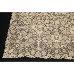A richly decorated rectangular tablecloth featuring floral motifs in linen and lace, with twelve matching napkins