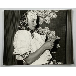 Fotografia kobiety w stroju ludowym na tle koniakowskiej koronki
