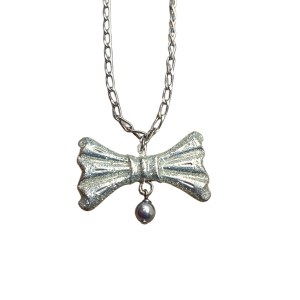 Necklace with cream pendant in the shape of a bow