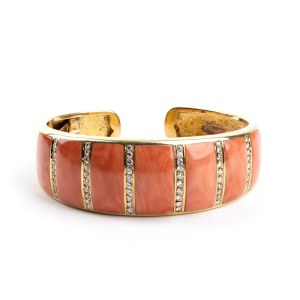 A gold open bangle bracelet featuring an elegant blend of coral and diamonds