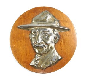 [HARCERTY]. Relief portrait of Robert Baden-Powell done in white metal, mounted on a round wooden backing....