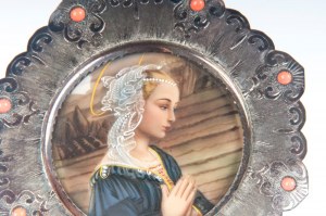 Lot of two miniatures: Mid 20th century 8.5 x 10 cm; diameter 9.7 cm one in a round shape with a Madonna printed within an octagonal silver and coral frame; the other in a rectangular shape with a bucolic scene with characters painted within a brass and b