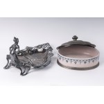 Lot of two pewter pocket empties France, first half of the 20th century 17 x 27 x 23.5cm; 14 x 21 x 17.5 cm one with an open triangular shape with a lady holding a stylised leaf, the other with an oval-shaped box with a pewter base and lid and a ceramic b