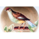 Lot of two knife plates 24.6 x 2.6 cm in polychrome porcelain, with a gilded brim and a pure gold rim. White background with a reproduction of a bird within a gilded reserve. On the back, a lowered background with a ring and a manufacturing signature in b
