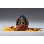 A small painted clay Tza Tza wrapped in a piece of silk fabric for daily Buddhist worship. Tibet or Nepal, 20th century.