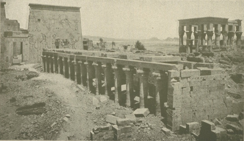 Wiz. 33 Widok ruin z egipskich świątyń z czasów Ptolemeuszów na wyspie Philae. Mała świątynia na prawo u góry, z czasów późniejszych. Na lewo pomiędzy pylonami, które są pokryte rzeźbami, drzwi wchodowe.